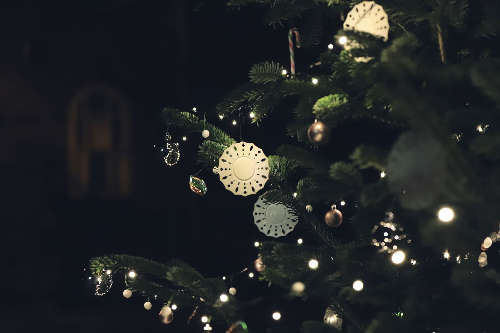 Árvore de Natal iluminada à noite, com enfeites brancos e luzes pequenas (foto de banco de imagens, não é o ParkShopping)