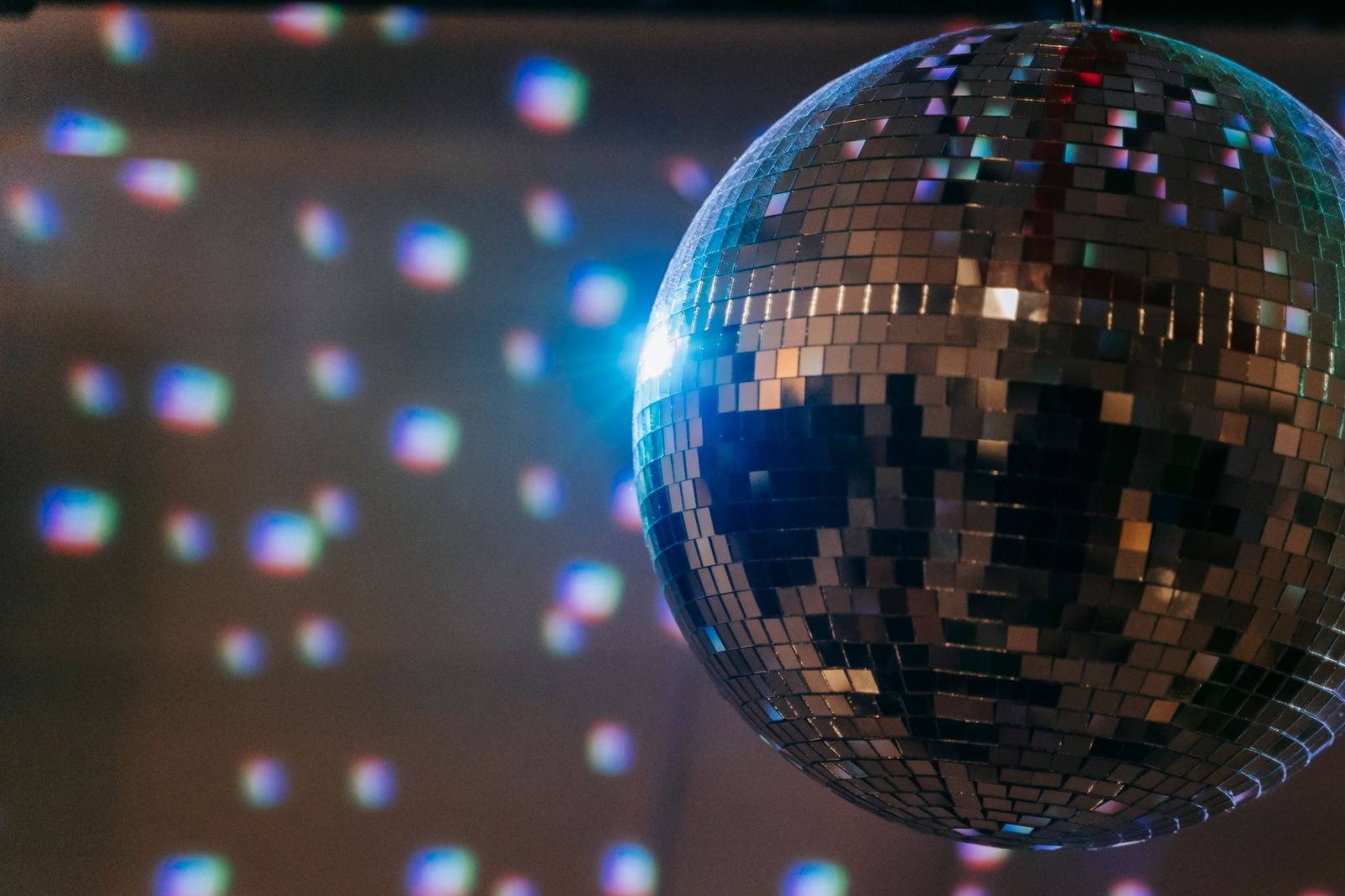 Globo de espelhos de discoteca refletindo luzes azuis e rosadas na parede