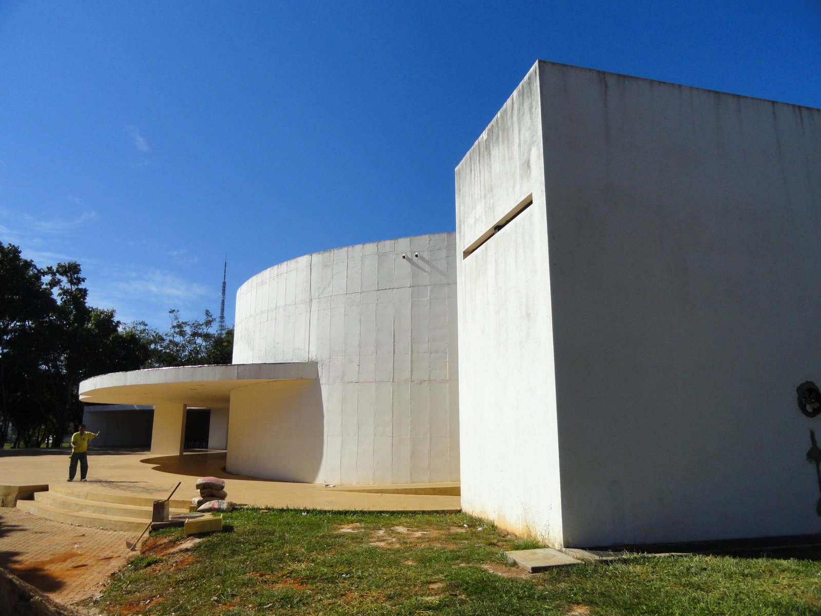 Fachada curva de concreto branco do Clube do Choro de Brasília, com a Torre de TV ao fundo