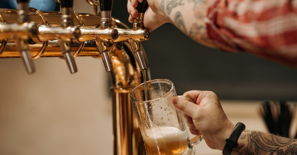 Bartender tira chope em torneira dourada em um bar (foto ilustrativa)