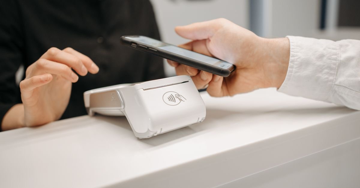 Cliente aproxima celular de máquina de pagamento em balcão de estabelecimento comercial