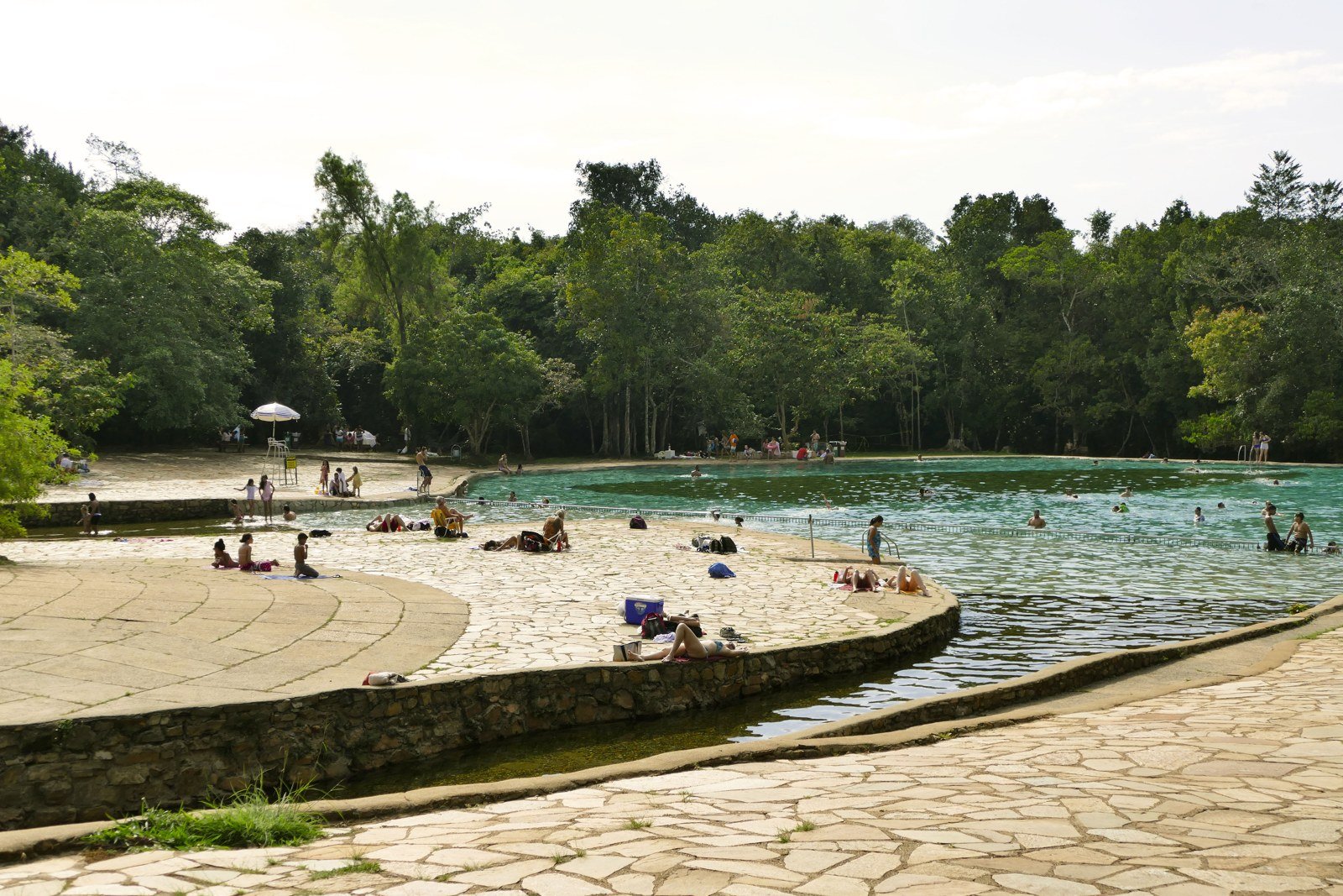 Piscina de água corrente do Parque Nacional de Brasília, com deck de pedra, banhistas e mata ao fundo