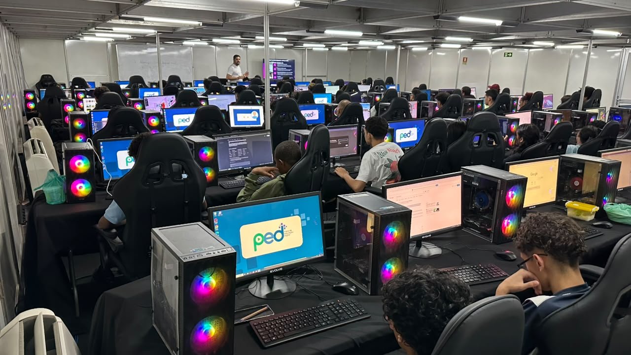 Visão ampla da sala do PED em Ceilândia, com fileiras de computadores e alunos em aula