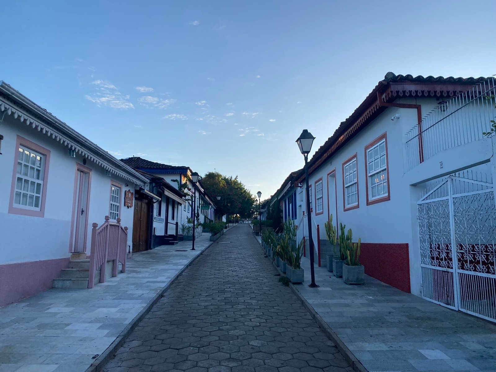 Rua de pedra do centro histórico de Pirenópolis com casario branco e postes de luz