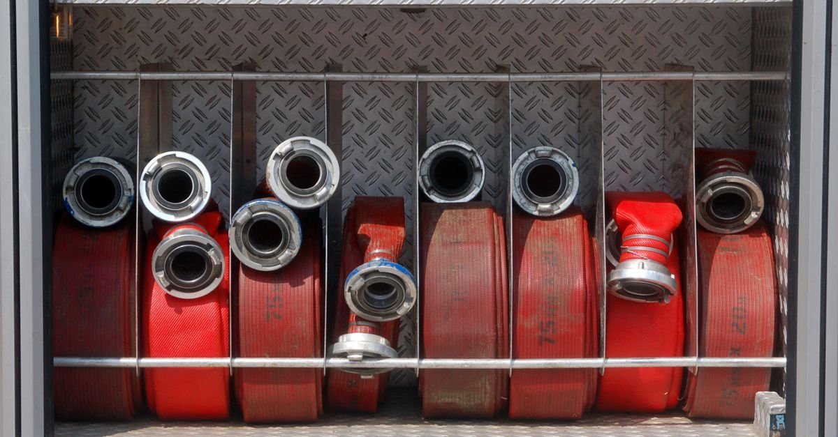 Mangueiras de combate a incêndio enroladas no compartimento de um caminhão de bombeiros