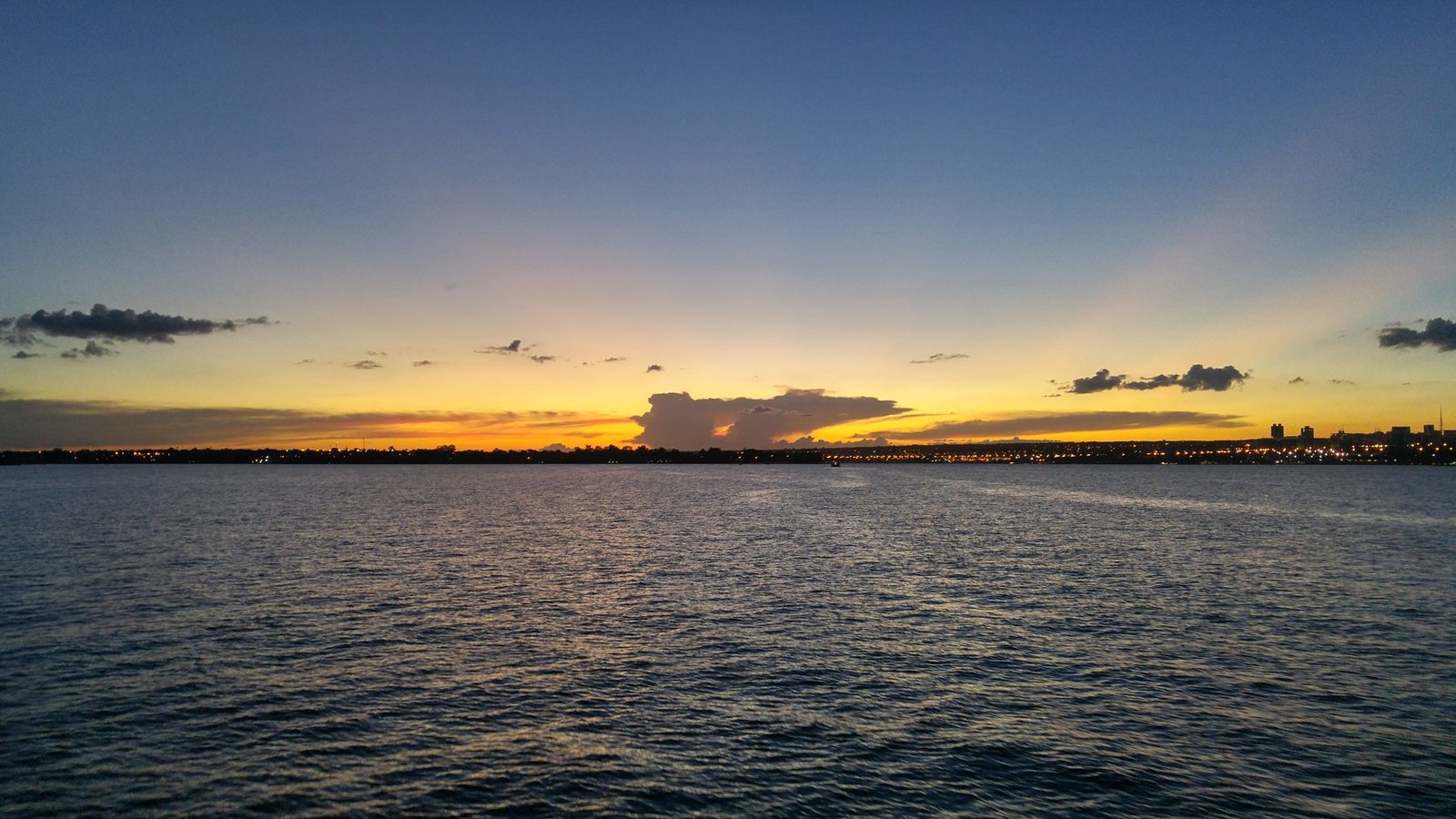 Pôr do sol sobre o Lago Paranoá, com a silhueta de Brasília ao fundo