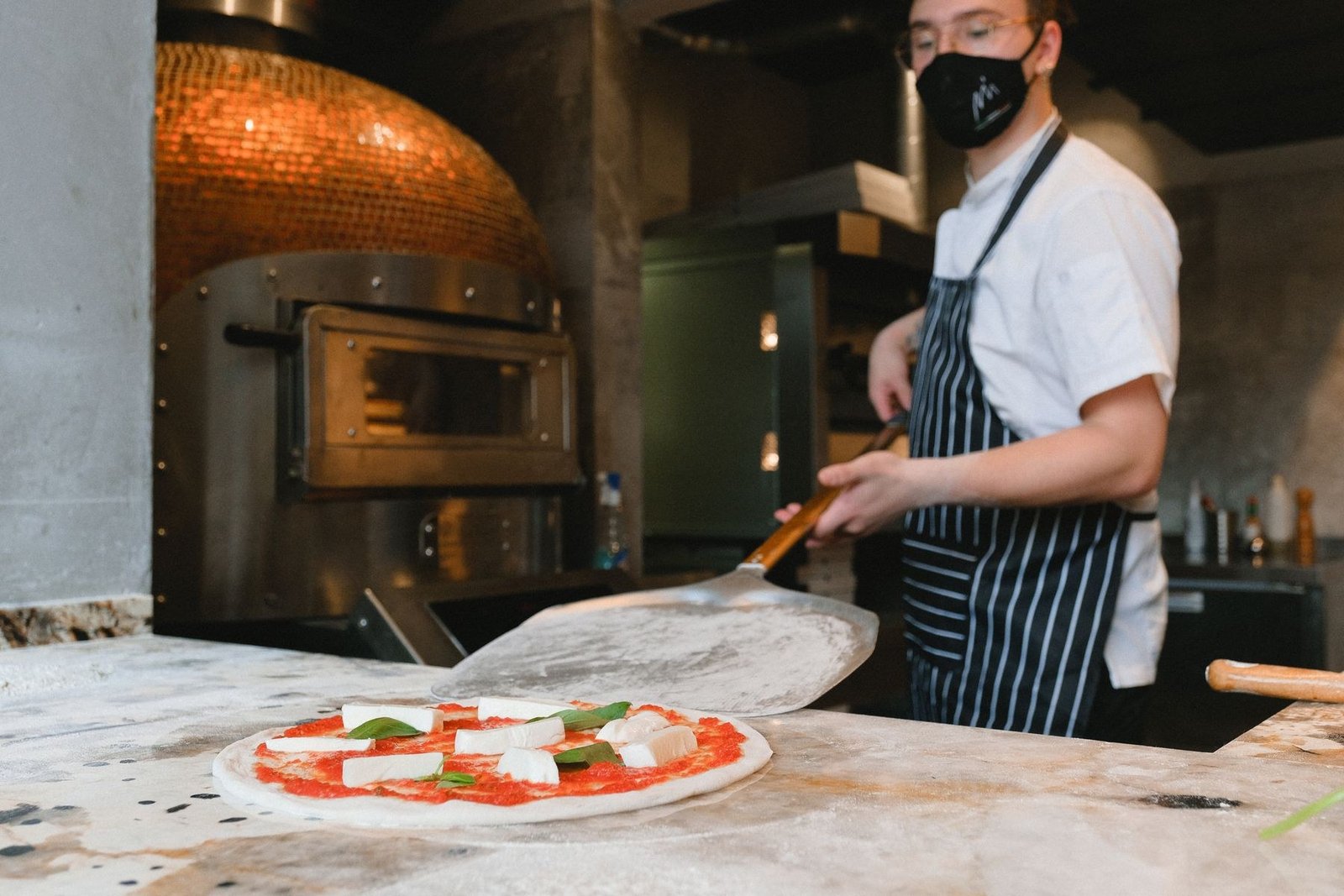 Pizzaiolo prepara pizza napolitana diante do forno a lenha