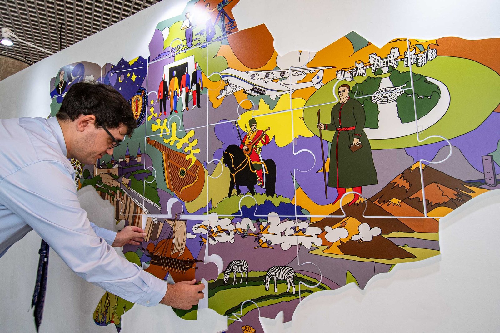 Homem encaixa uma peça de um painel colorido em forma de quebra-cabeça que reproduz o mapa da Ucrânia