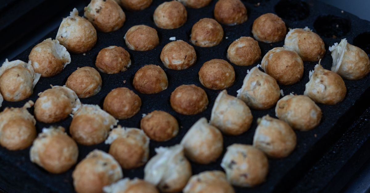 Bolinhos de takoyaki sendo preparados em chapa própria durante festival japonês