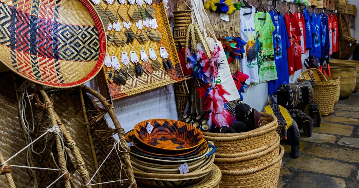 Cestos e bandejas de palha, adereços de pena e peças de artesanato expostos numa loja, em imagem de arquivo que não é da Quituart