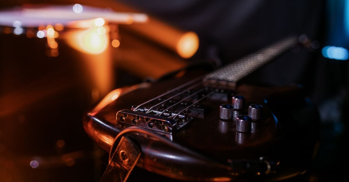 Guitarra elétrica apoiada em um palco com iluminação quente ao fundo