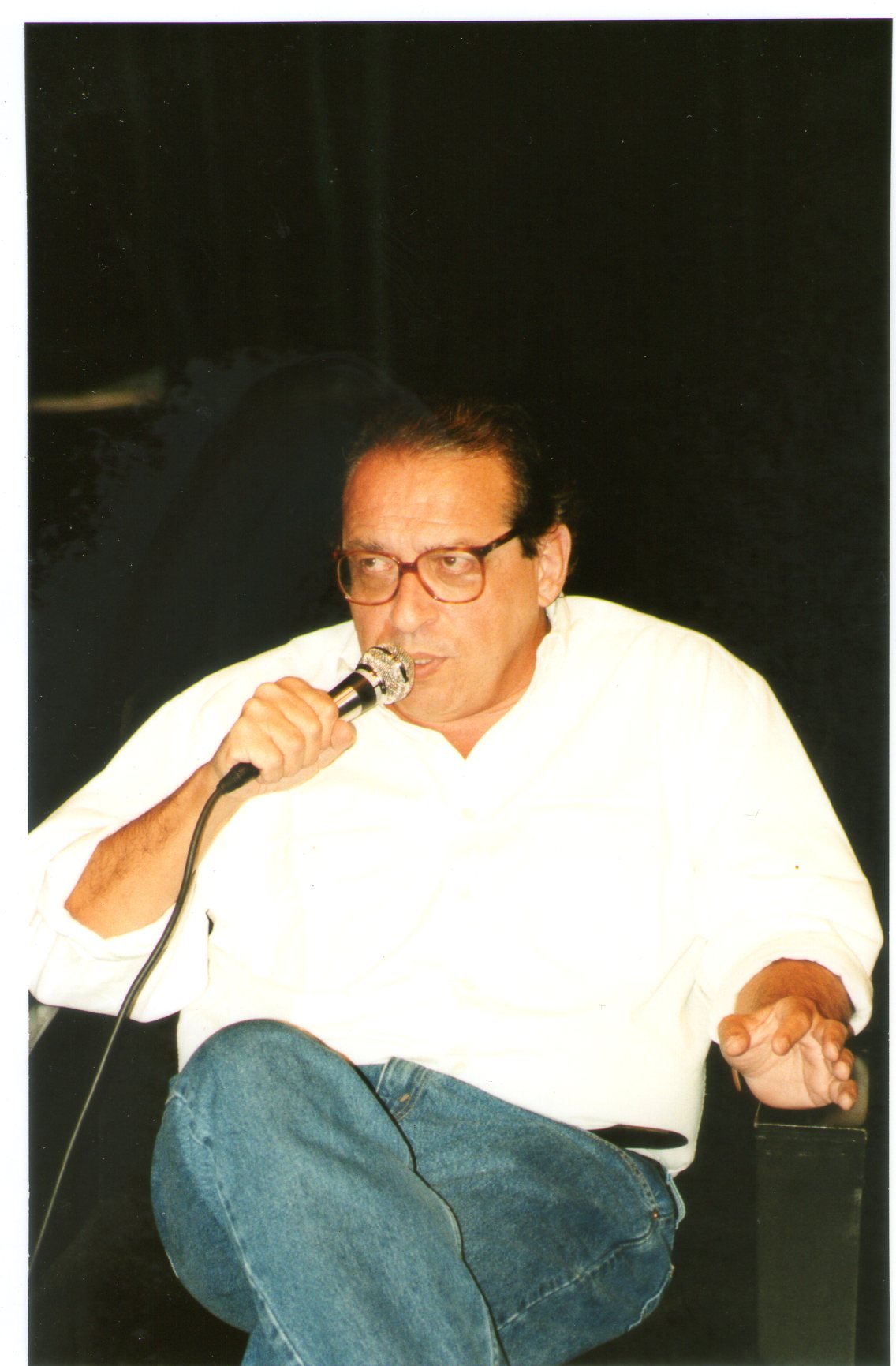 Ruy Castro fala ao microfone sentado, em foto de arquivo