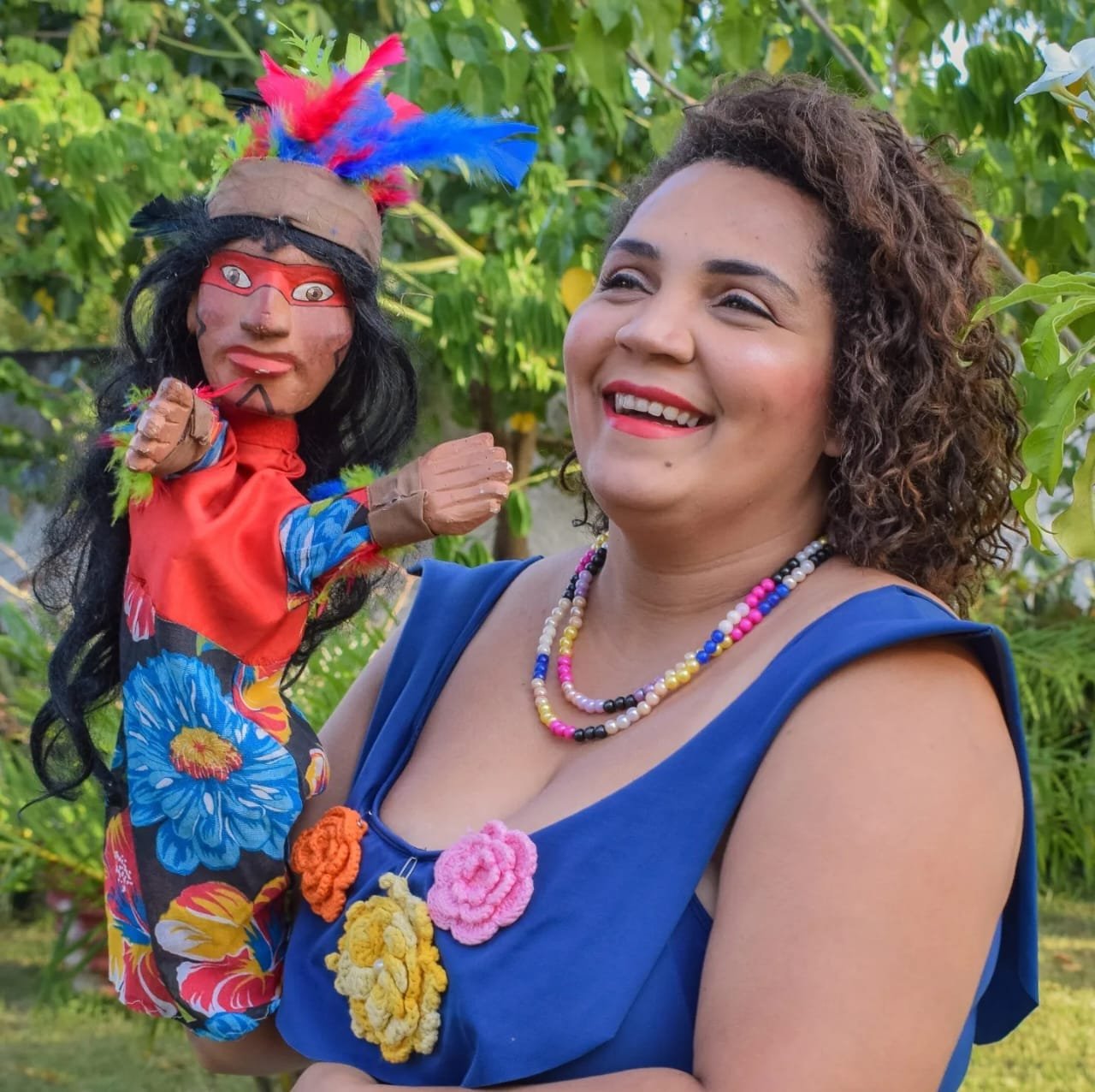Mamulengueira segura um boneco de mamulengo colorido ao ar livre