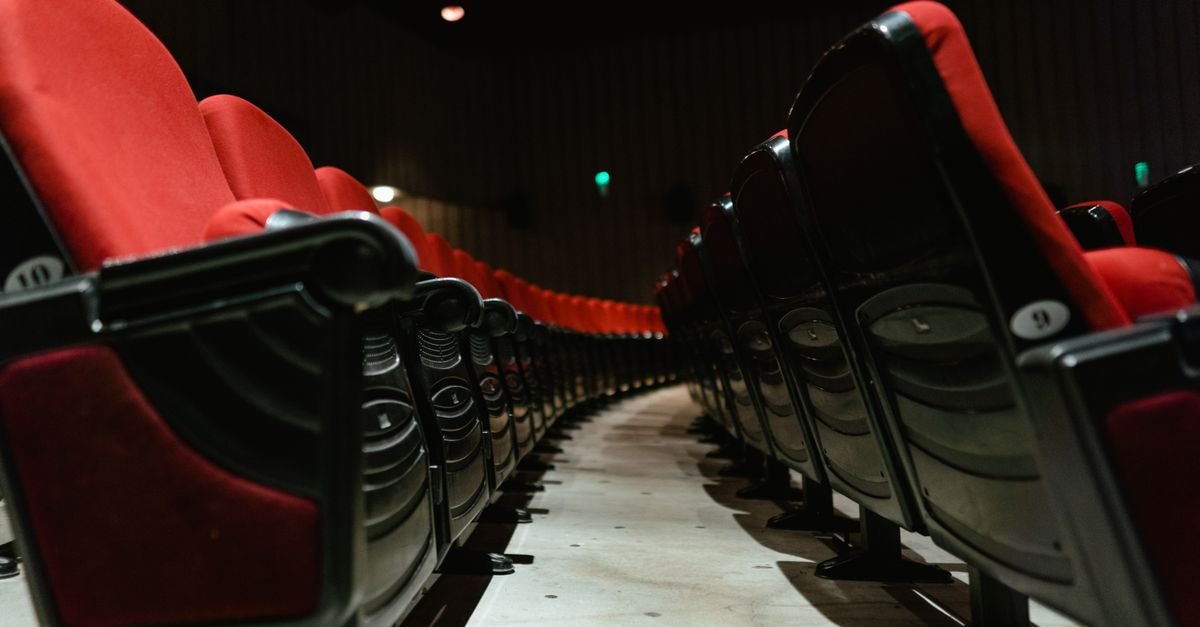 Fileiras de poltronas vermelhas vazias em sala de teatro