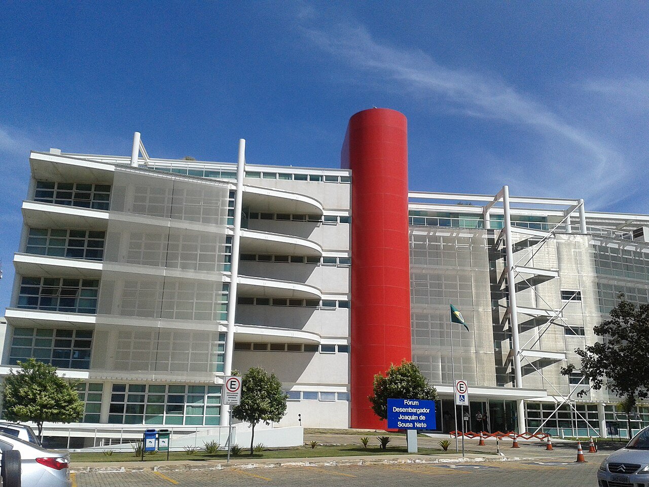 Fachada de fórum do TJDFT com torre vermelha e bandeira do Distrito Federal