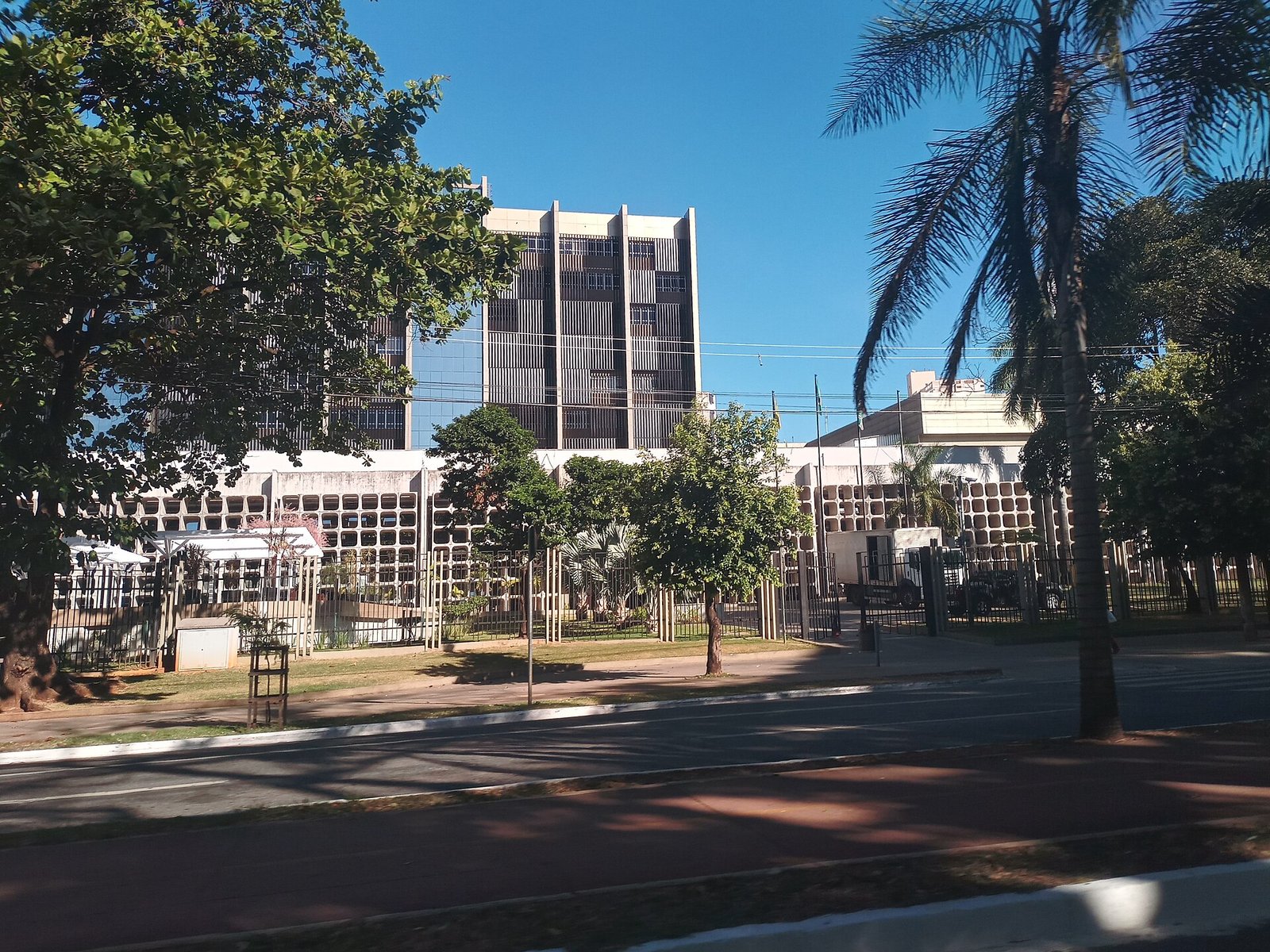 Fachada do prédio do Tribunal de Justiça de Goiás vista da rua, com árvores em primeiro plano