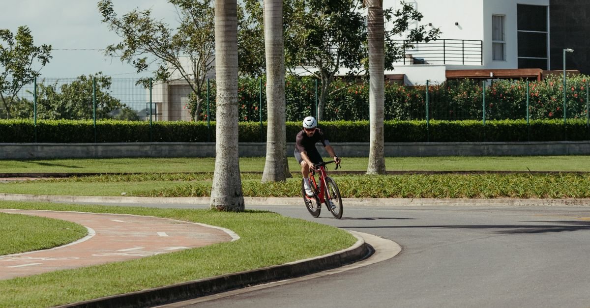 Ciclista pedalando por ciclovia arborizada em parque urbano durante o dia