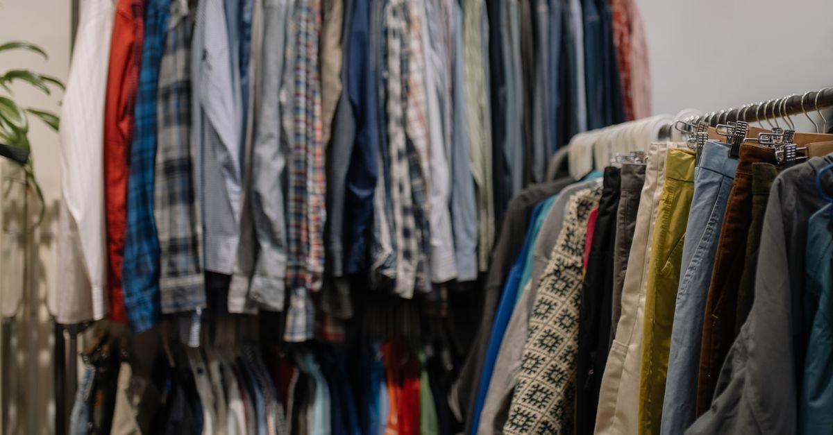 Araras com camisas e calças de segunda mão organizadas em cabides