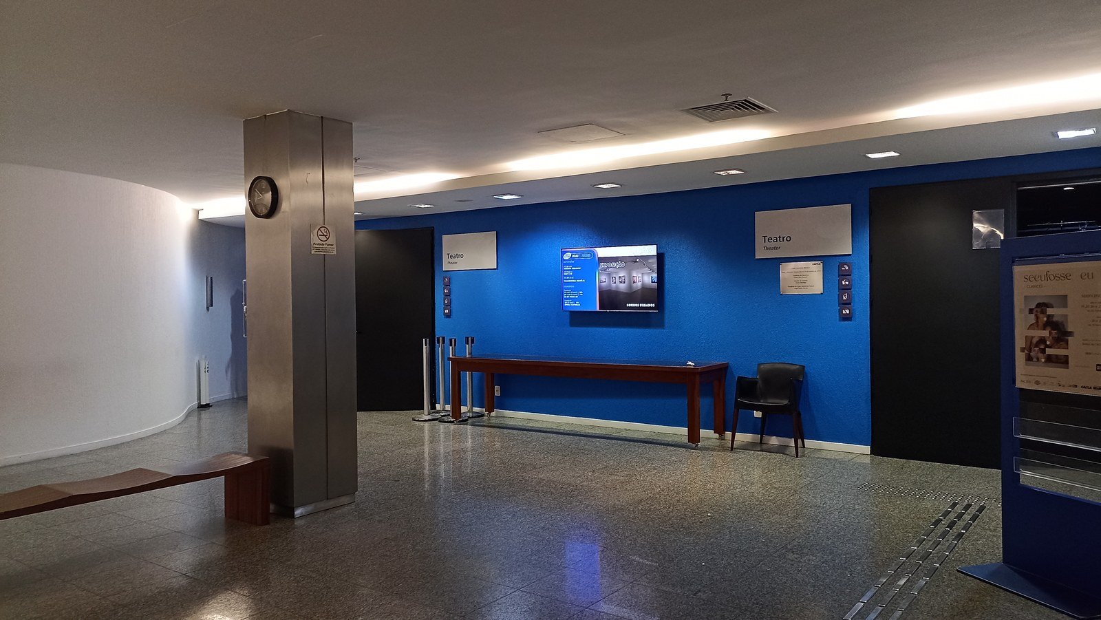Foyer do teatro da Caixa Cultural Brasília, com a sinalização Teatro sobre a parede azul