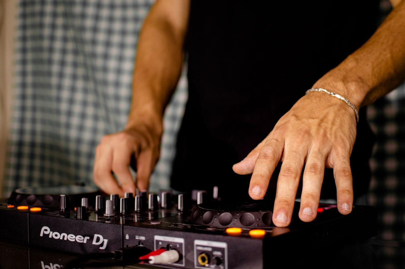 Mãos de um DJ sobre os botões e o jog de um controlador, em foto de arquivo