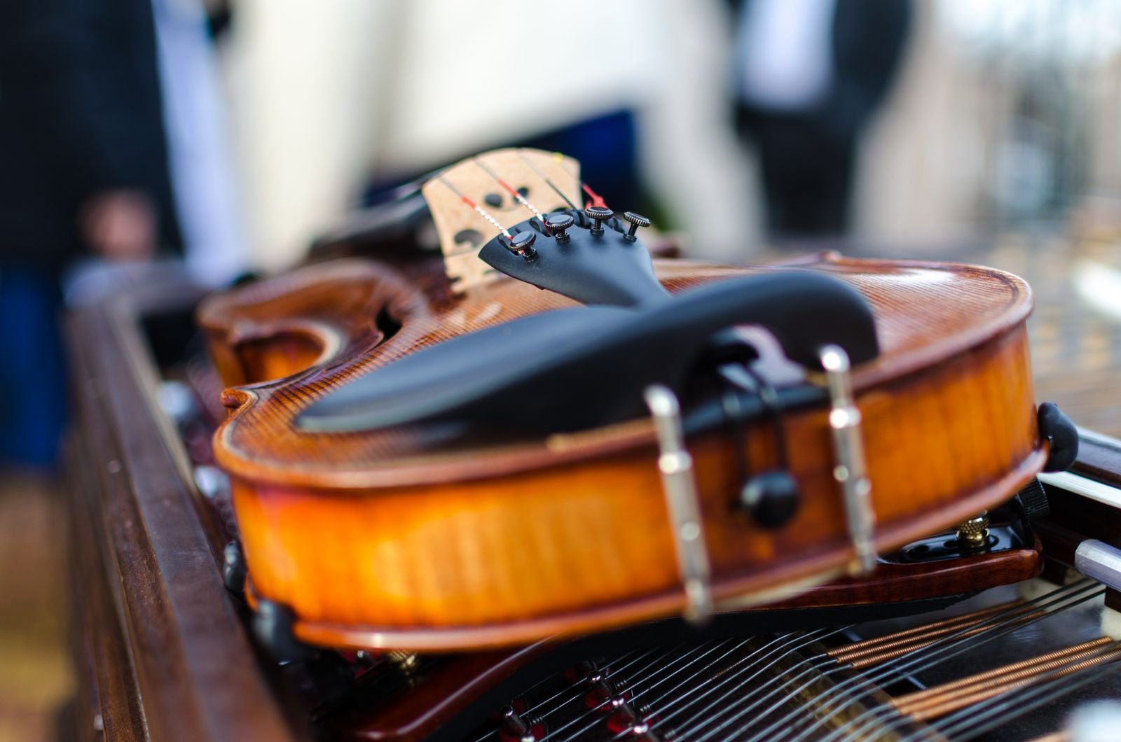 Violino de madeira apoiado sobre as cordas de um piano (foto de arquivo)