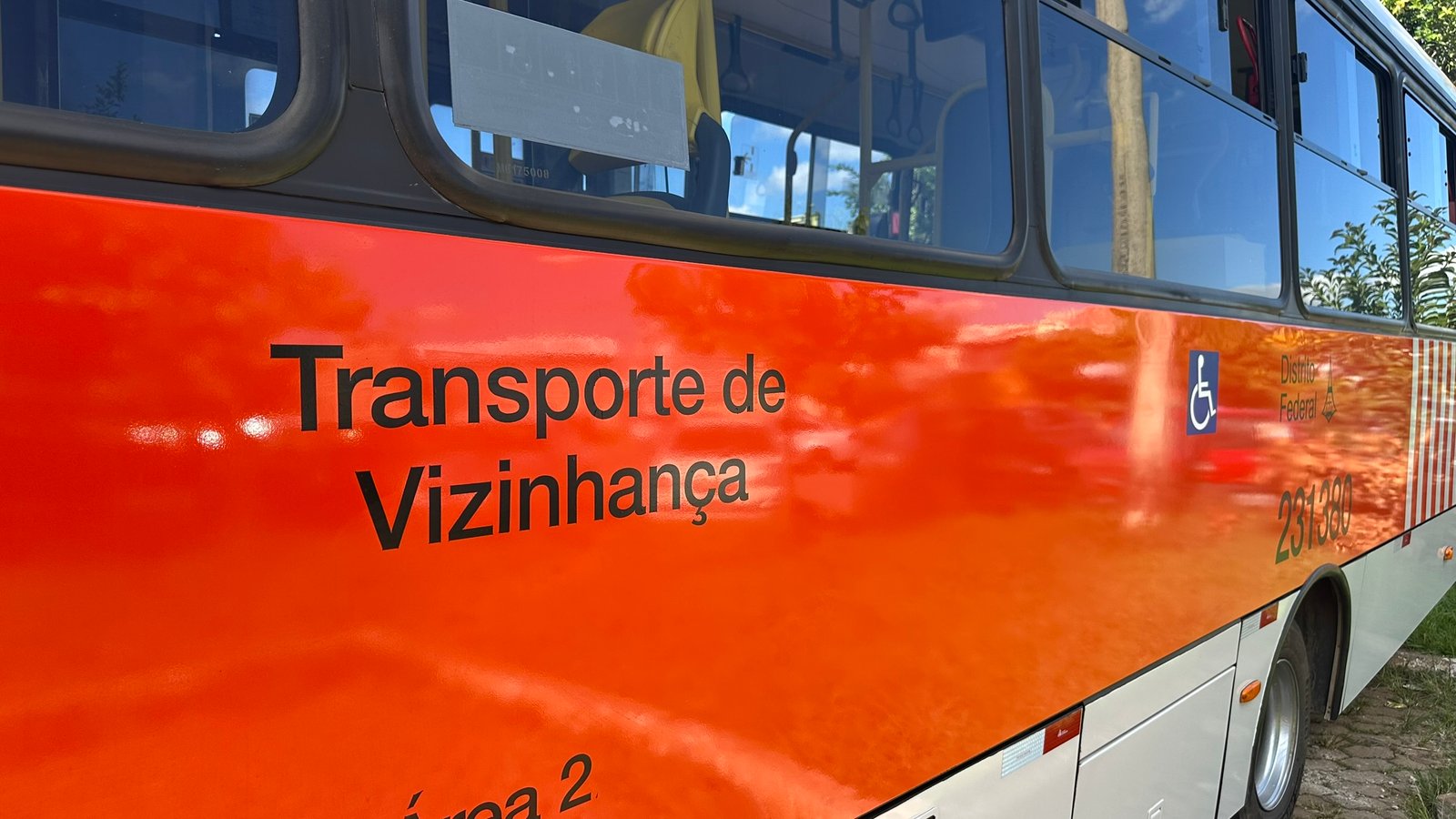 Lateral de ônibus laranja do serviço de transporte de vizinhança do Distrito Federal, com a inscrição Transporte de Vizinhança